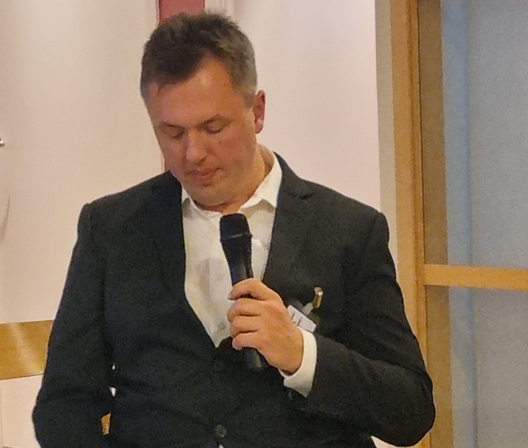 Johan Steirud talar. Har en svart kostym, vit skjorta, sitter i rullstol. 